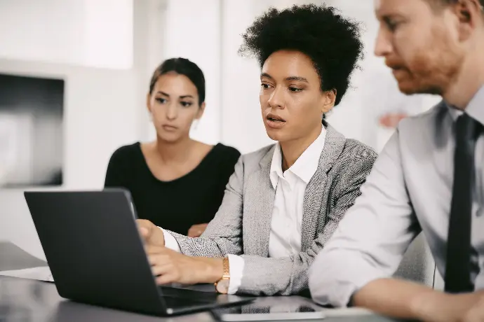 mulher no computador com mais duas pessoas ao lado