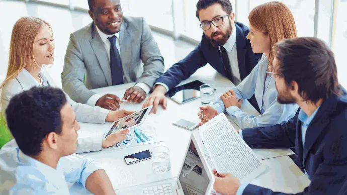 Mesa de reunião com 6 pessoas conversando